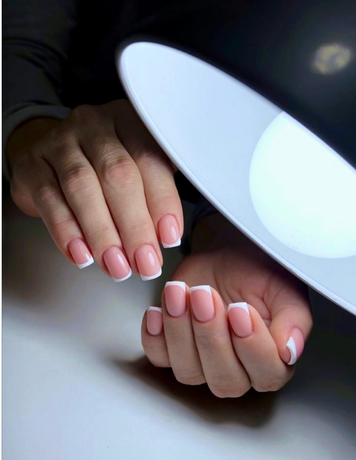 French manicure under a salon lamp